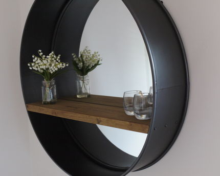 Large round industrial metal wall mirror with wood shelf.