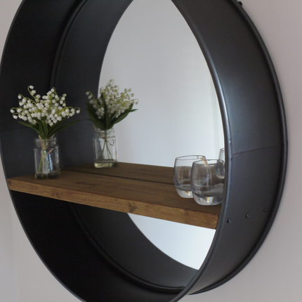 Large round industrial metal wall mirror with wood shelf.