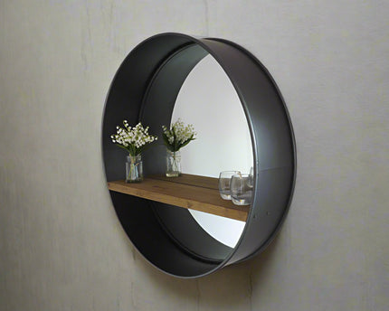 Large round industrial metal wall mirror with wood shelf.